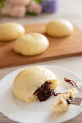 Germknödel oder Hefeklöße mit Pflaumenmusfüllung auf weißem Teller und hellem Holzuntergrund