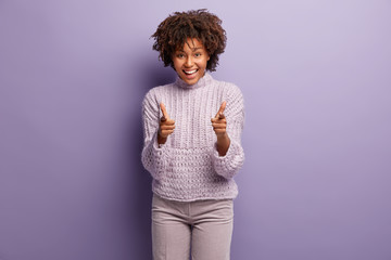 People, happiness, choice concept. Satisfied Afro American woman makes finger gun gesture, smiles...