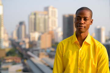 Young bald African businessman against view of the city