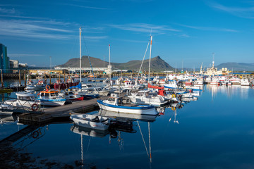 Fototapeta na wymiar Marine port for fishing boats and private yachts in Akranes town in western coast of Iceland. Akrafjall mountain massif is at background.