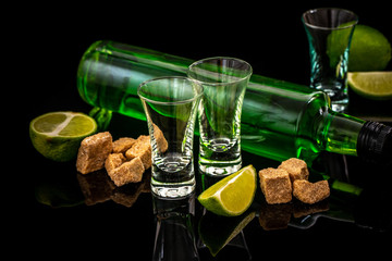 Traditional italian or czech liqueur or bitter with lime slices. Three absinthe glass, cube brown sugar on dark background. free space for text. the concept of elite alcohol