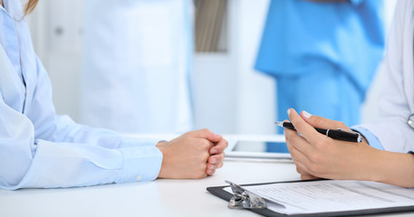 Fototapeta premium Doctor and patient discussing something, just hands at the table, white background