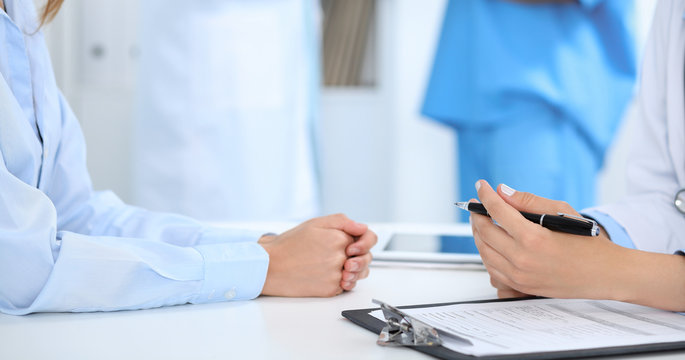 Doctor and patient discussing something, just hands at the table, white background