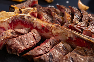 porterhouse t-bone steak is grilled sliced on a piece on black background. rustic style, top view