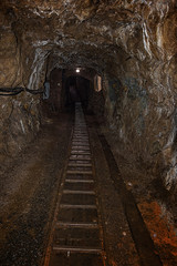 Fototapeta na wymiar Empty old abandoned mine shaft with rusty railway