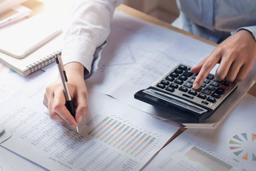 finance and accounting concept. business woman working on desk using calculator to calculate in...