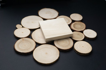 Pine tree cross-sections with annual rings and wooden square onblack surface. Lumber piece close-up shot, top view.