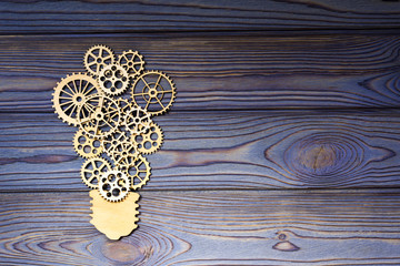 Wooden gears in the form of a light bulb on a wooden background. the concept of the mechanism of the business idea.