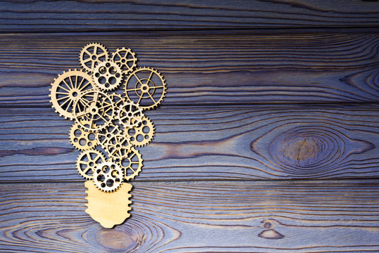 Wooden gears in the form of a light bulb on a wooden background. the concept of the mechanism of the business idea.