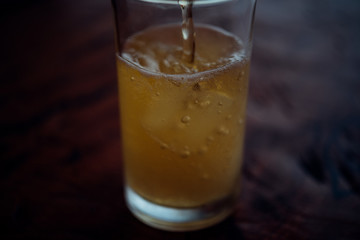 Pouring beer water in to glass with ice and froth