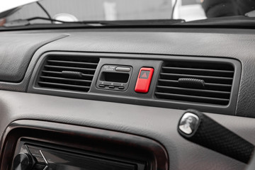 Fototapeta premium Close-up on emergency button in red color with clock near the duct in the interior of an old Japanese car in gray after dry cleaning
