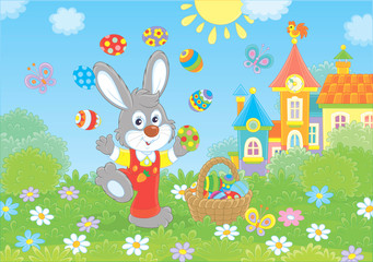 Little Bunny juggling with colorful Easter eggs on a green lawn in front of a small town on a sunny spring day, vector illustration in a cartoon style