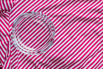 Glass clean ashtray for quenching cigarette butts on striped swimsuit.