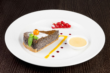 Poppy seed cake with winter cherry, red currant and vanilla sauce on a dark wooden background