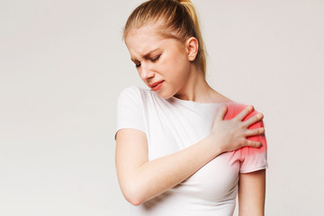 Young woman suffering from pain in shoulder
