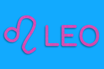 Symbol of astrological sign and word leo cut out of purple paper on blue table. Top view. Horoscope concept