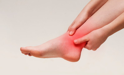 Woman suffering from pain in ankle closeup