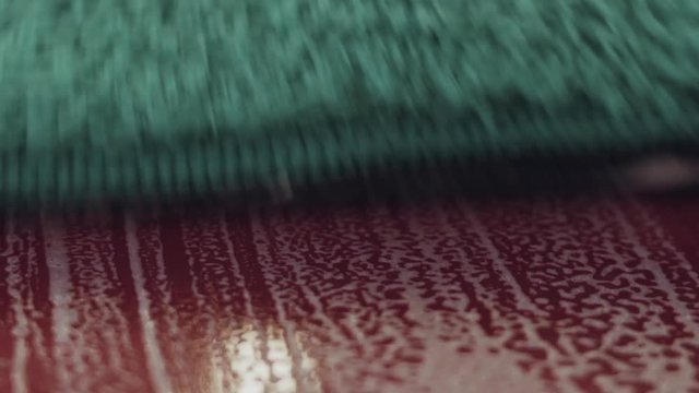 Slow motion handheld closeup of car paint deep cleaning with mitten