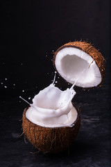 Two halves of a coconut and splashing coconut milk 