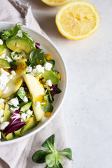 Mix salad with corn, apple, avocado and fresh farm cottage cheese. Healthy and diet food concept. Light concrete background. Copy space.