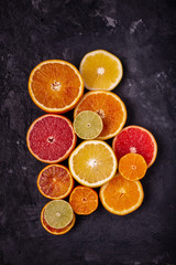 Various types of citrus fruit cut into slices on a dark background