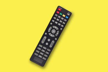 Single black plastic remote control for different multimedia devices in center on yellow...