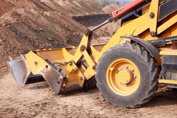 Excavator loader working at ground area, digging process. Yellow bucket. Outdoors, copy space.