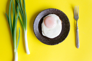 Sunny side up. Fried eggs with green onions on yellow background