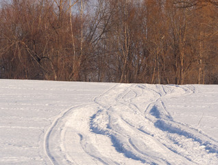 Obraz premium Traces of a snowmobile in the forest by the river.