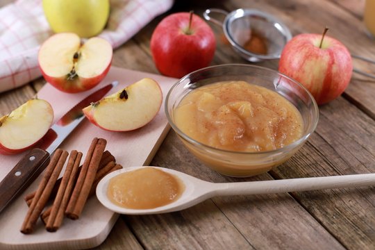 homemade apple jam, with fresh apples and spices with wooden spoon on wooden rustic table