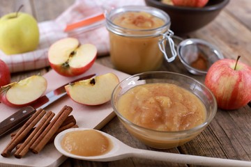 homemade apple jam, with fresh apples and spices with wooden spoon on wooden rustic table