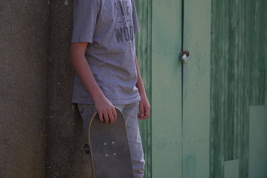 chico joven con skate en zona industrial verde