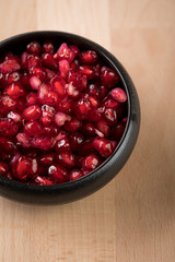 Granatapfel Kerne in schwarzer Porzellan Schale auf Holz Hintergrund