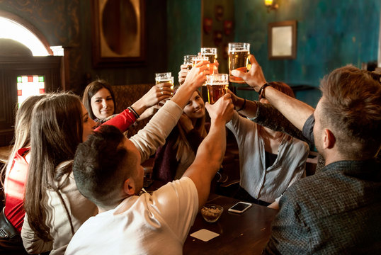 group of people celebrating in a pub drinking beer