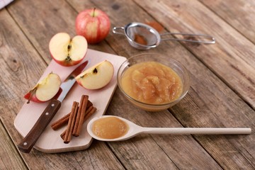 homemade apple jam, with fresh apples and spices with wooden spoon on wooden rustic table