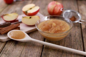 homemade apple jam, with fresh apples and spices with wooden spoon on wooden rustic table