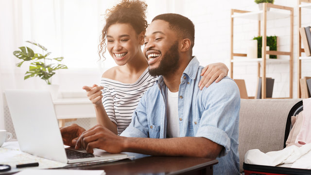 African-american couple searching tour online on laptop