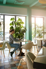 The girl works at the computer in a cafe with fresh flowers