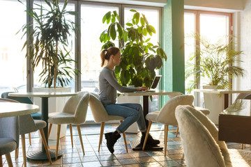 The girl works at the computer in a cafe with fresh flowers