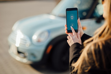 Woman using Smartphone near the car. Mobile phone apps for car owners concept.