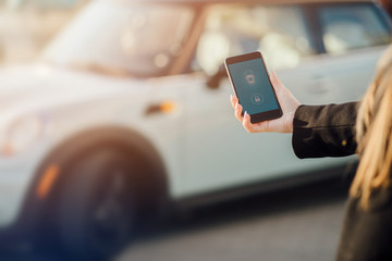 Woman using Smartphone near the car. Mobile phone apps for car owners concept.