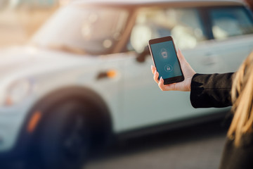 Woman using Smartphone near the car. Mobile phone apps for car owners concept.