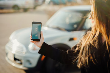 Woman using Smartphone near the car. Mobile phone apps for car owners concept.
