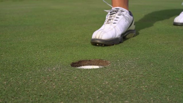 Man golfing and putting in hole. Male player on a golf course - Slider shot