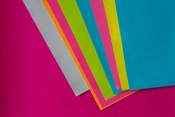 texture of few sheets of coloured paper and fuchsia background
