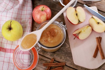 homemade apple jam , apple puree, with cinnamon, fresh apples and a wooden spoon on wooden rustic table