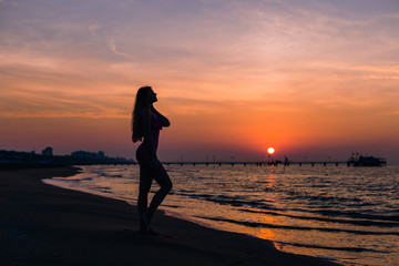 Fototapeta na wymiar silhouette girl with long hair and fit body posing on the beach