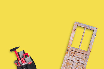 Full textile bag for instrument for repair and old unpainted worn wooden door in center on yellow backdrop with copy space for your text. Flat lay. Building or repair concept