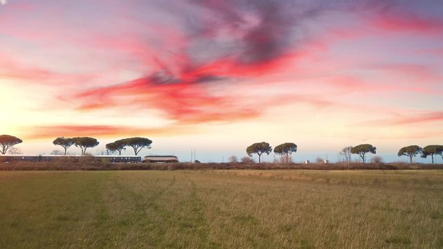 Treno hotel Orient Express in transito nella natura di fronte a un tramonto.