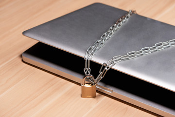 Heavy chain with a padlock around a laptop on table.